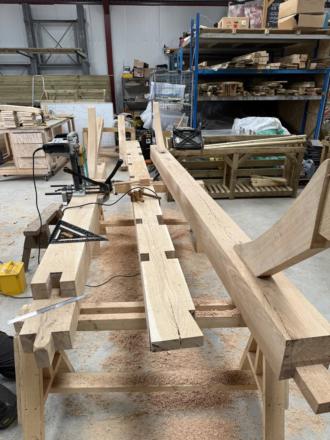 Jointed oak beams and curved braces laid out on workshop trestles