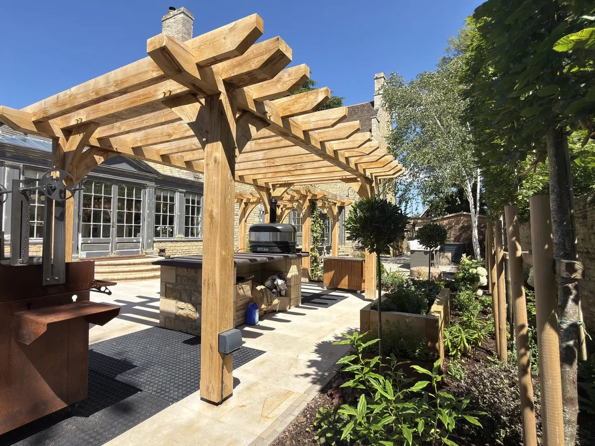 Installed oak pergola with curved braces sheltering an outdoor kitchen and patio