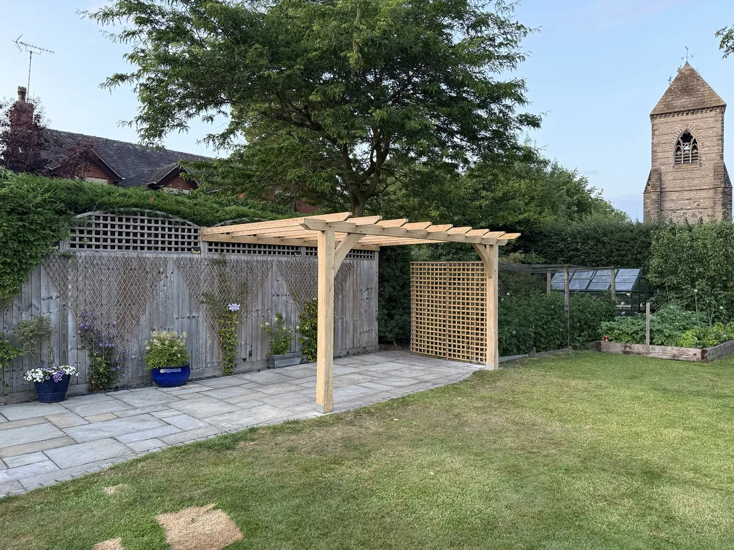 Bespoke oak pergola over a paved garden terrace with timber trellis