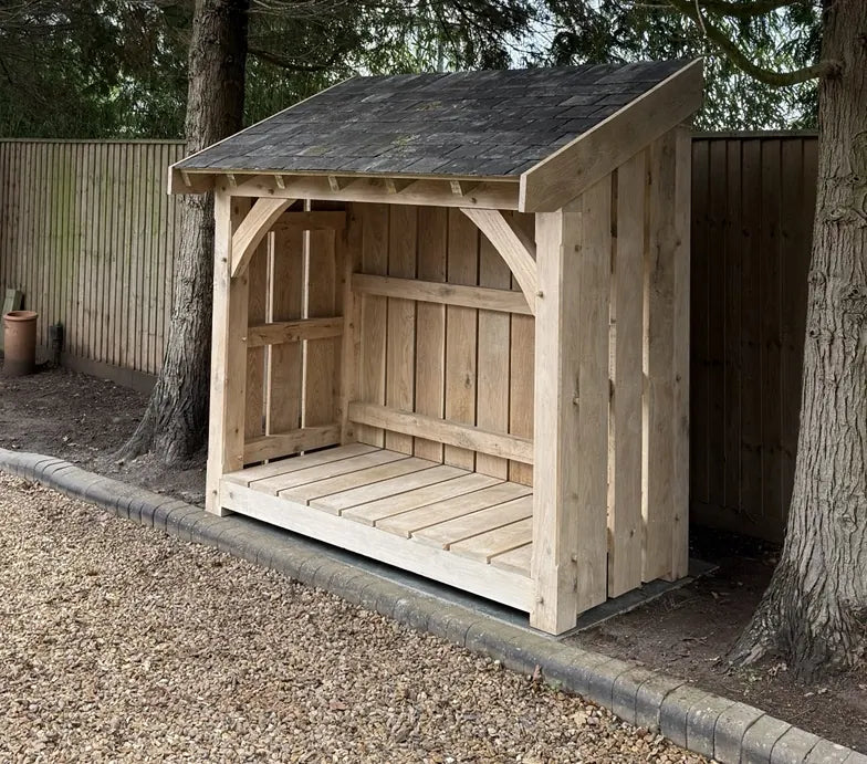 Handmade oak log store with a slate roof, curved braces and raised floor