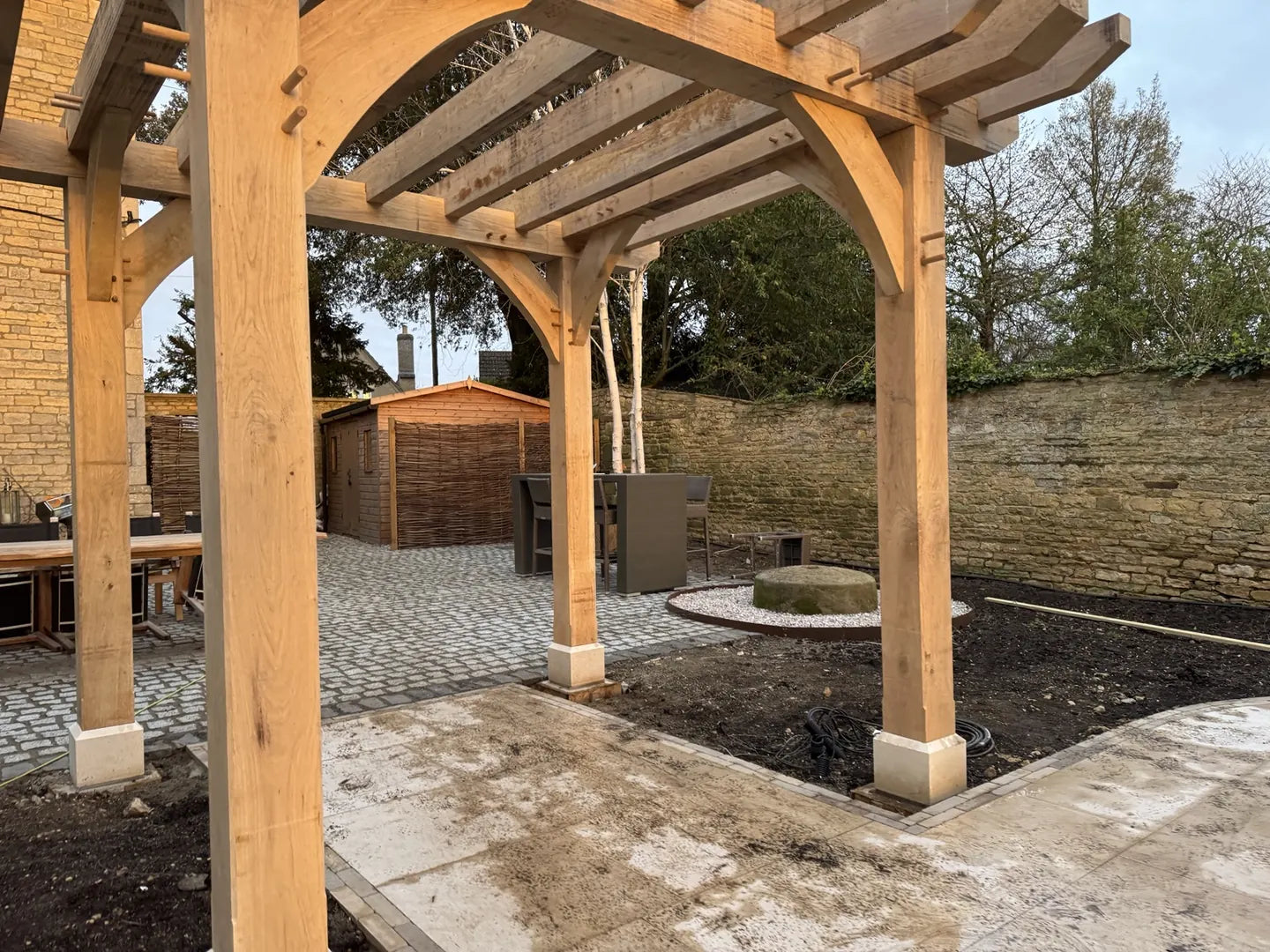 Oak pergola with pegged curved braces and posts on staddle stones