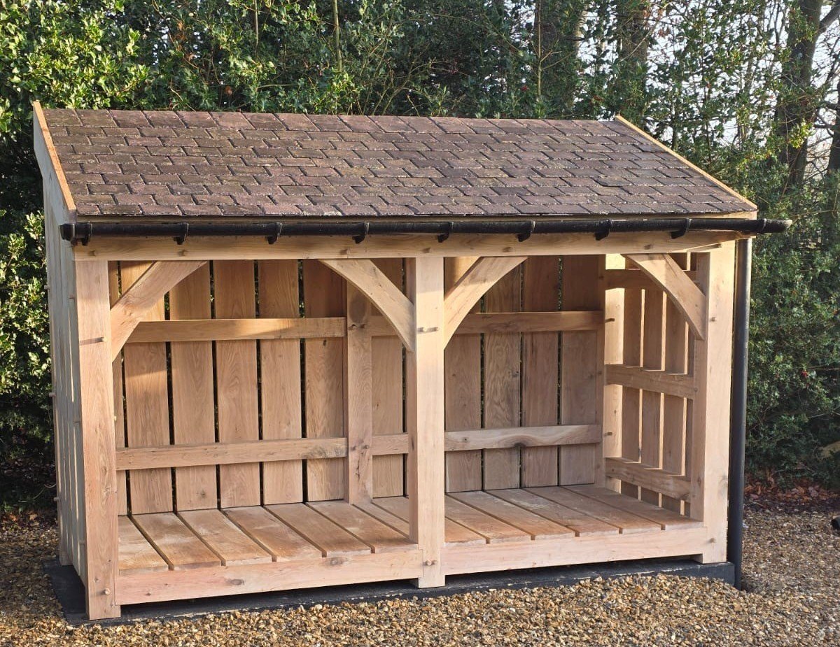 Two-bay French oak log store with a reclaimed Welsh slate roof